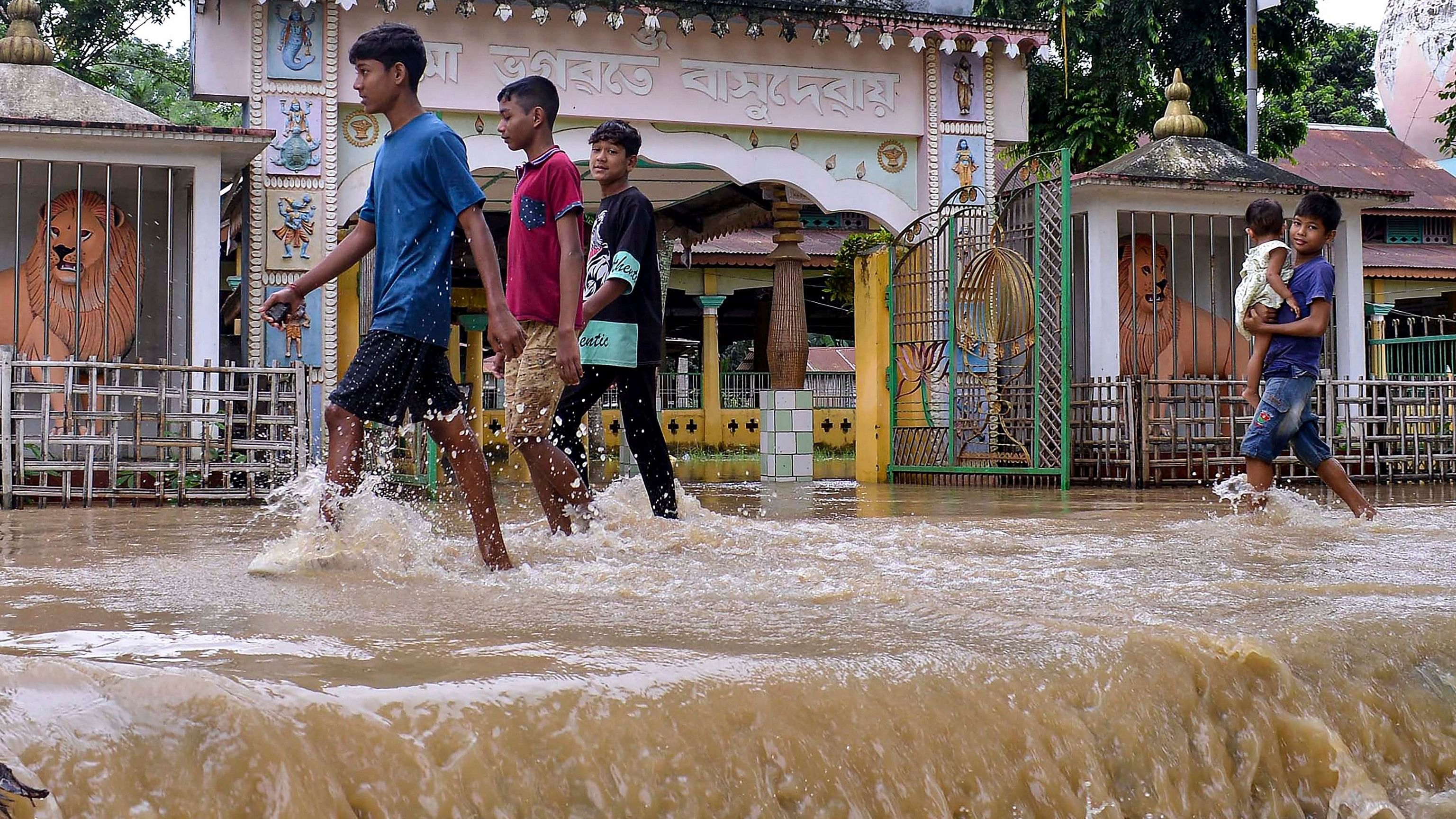 <div class="paragraphs"><p>People walk through a flooded area following rains, at Kampur, in Nagaon district, Assam, Thursday, June 20, 2024. </p></div>