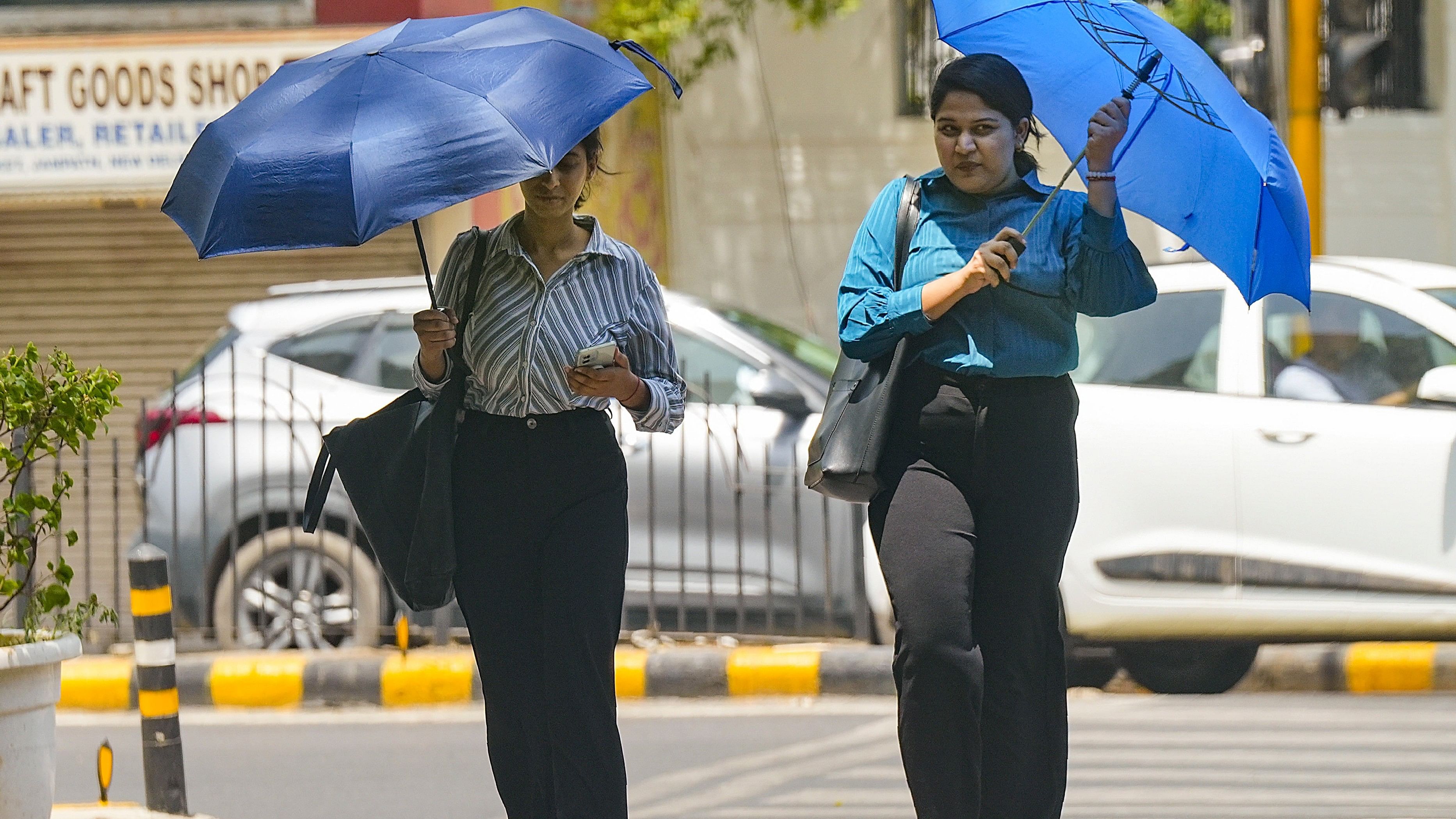 <div class="paragraphs"><p>Women cover themselves under umbrellas during heatwave, in New Delhi.</p></div>