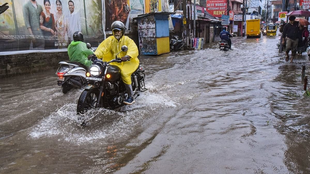 <div class="paragraphs"><p>Commuters wade through a flooded road amid rains in Kochi.</p></div>