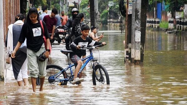 <div class="paragraphs"><p>People wade through a waterlogged road after heavy rainfalls, in Guwahati, Monday, June 17, 2024.</p></div>