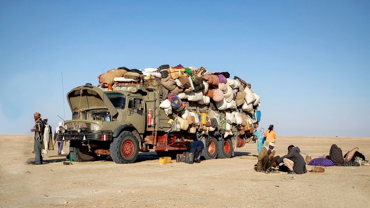 <div class="paragraphs"><p>Representative image showing migrants loading a truck in a dessert.</p></div>