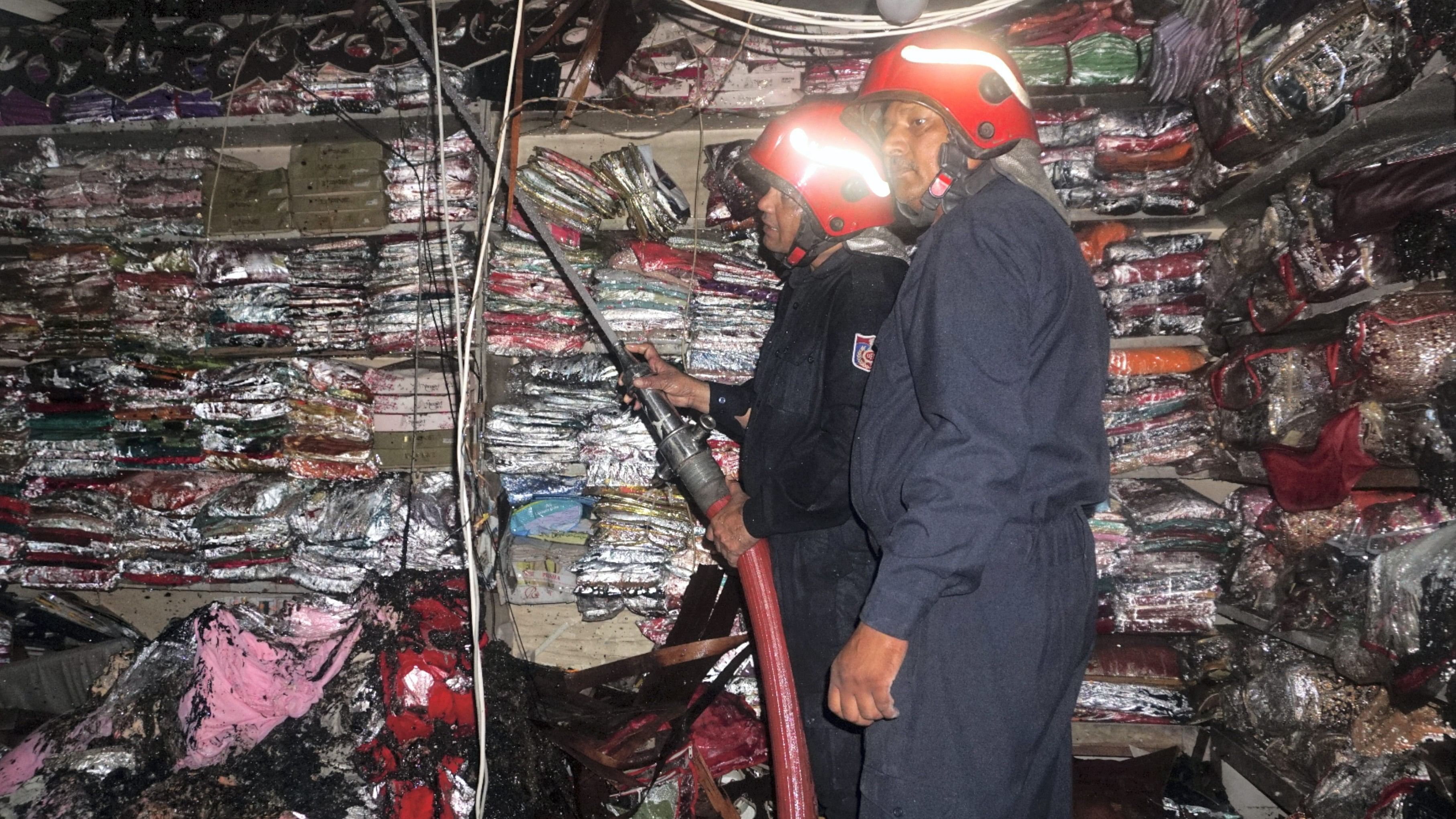 <div class="paragraphs"><p>Firefighters stand at a damaged shop after a fire broke out at Chandni Chowk on Thursday, in New Delhi.</p></div>