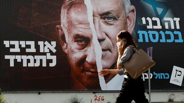 <div class="paragraphs"><p>A woman walks past a Blue and White party election campaign banner depicting its leader, Israeli Defence Minister Benny Gantz, alongside Israeli Prime Minister Benjamin Netanyahu ahead of the March 23 ballot, in Tel Aviv.</p></div>