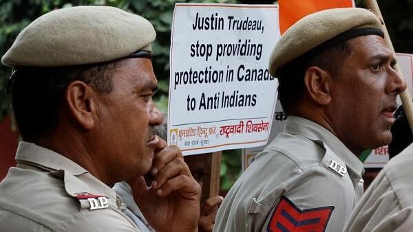 <div class="paragraphs"><p>Police officers stand as an activist  holds a placard during a protest against Canadian Prime Minister Justin Trudeau in New Delhi</p></div>