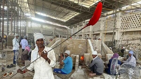 <div class="paragraphs"><p>A man carrying molten glass at the bangle making industry, in Firozabad, Monday, May 20, 2024</p></div>