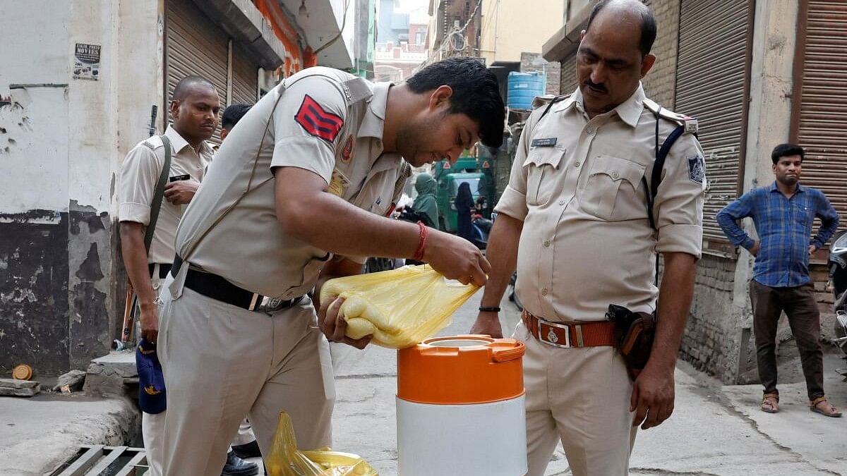 <div class="paragraphs"><p>A police officer pours sugar in a water container to make a sweet drink outside a polling station  in New Delhi.&nbsp;</p></div>