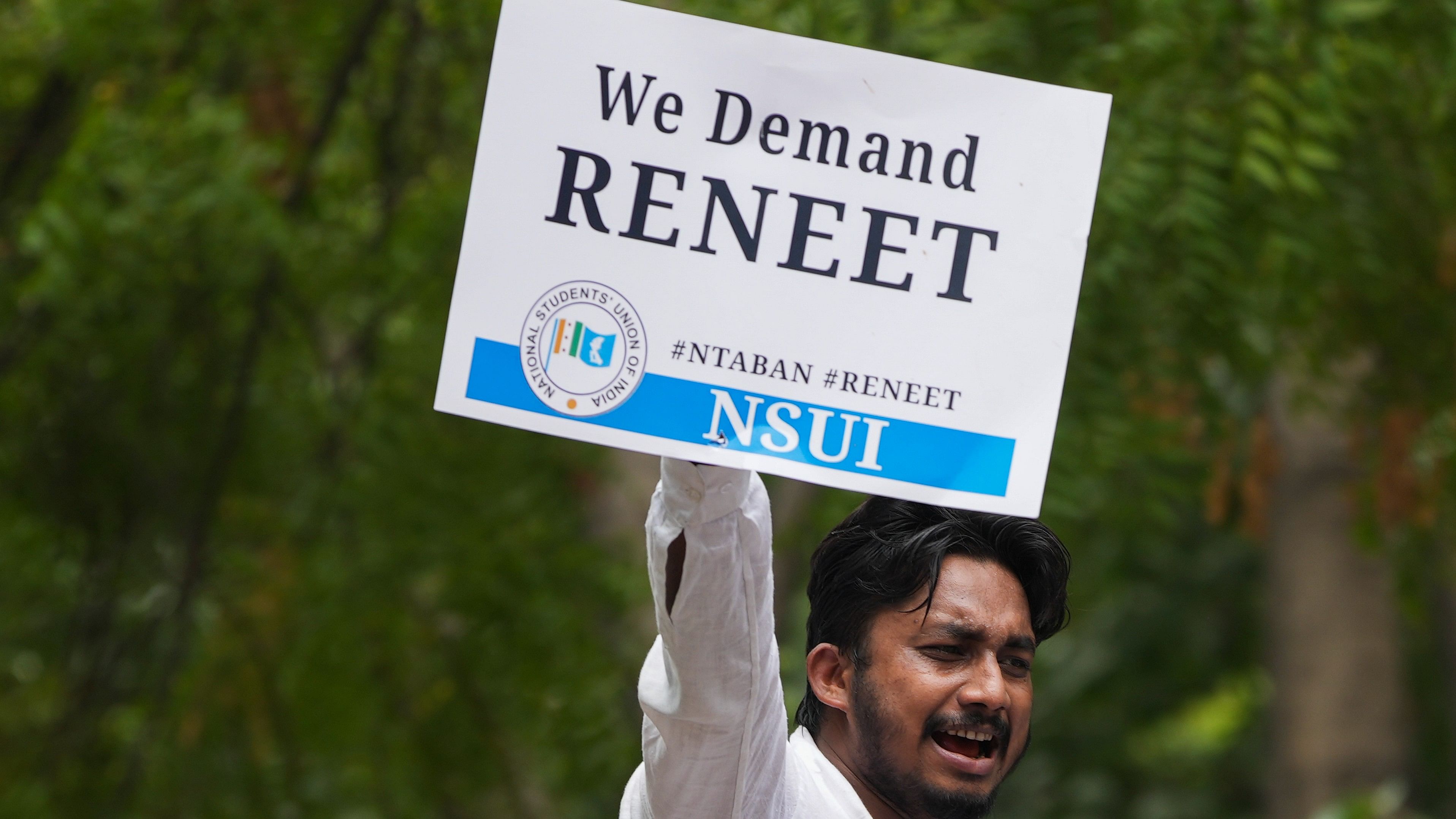 <div class="paragraphs"><p>An NSUI activist holds a placard during ‘Chhattra Sansad Gherav’ protest at Jantar Mantar against the alleged irregularities in NEET-UG and cancellation of UGC-NET exams, in New Delhi on Monday.</p></div>