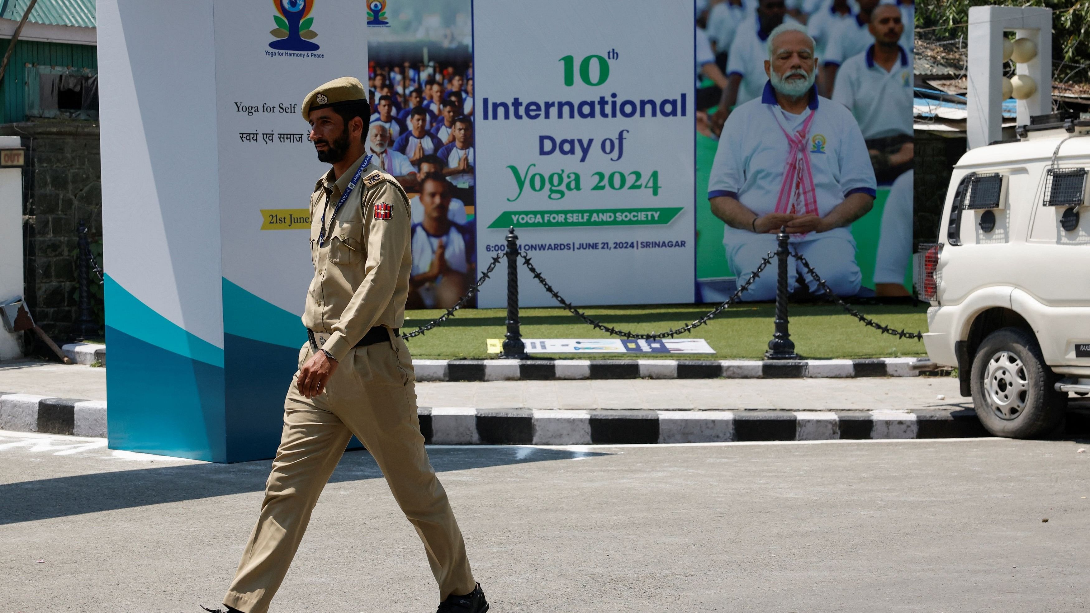 <div class="paragraphs"><p>An Indian security personnel walks past the hoarding featuring Prime Minister Narendra Modi performing Yoga, in Srinagar</p></div>