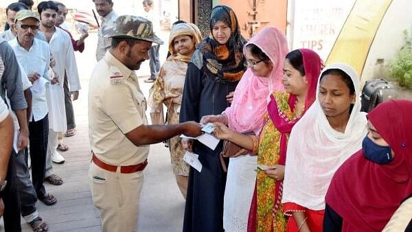 <div class="paragraphs"><p>A security personnel checks identification cards of people waiting in a queue at a polling station to cast their votes during the seventh and last phase of Lok Sabha elections, in Patna, Saturday, June 1, 2024.</p></div>