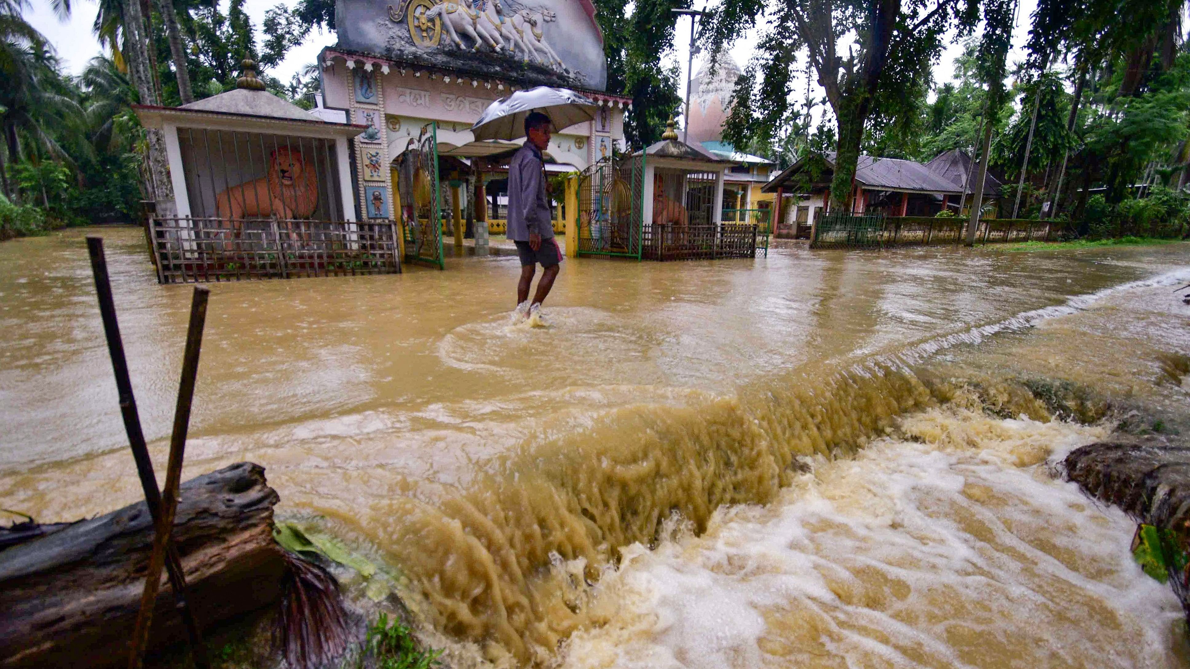 <div class="paragraphs"><p>A man walks through a flooded road following rains at Changchaki village, in Nagaon district of Assam, Tuesday, June 18, 2024. </p></div>