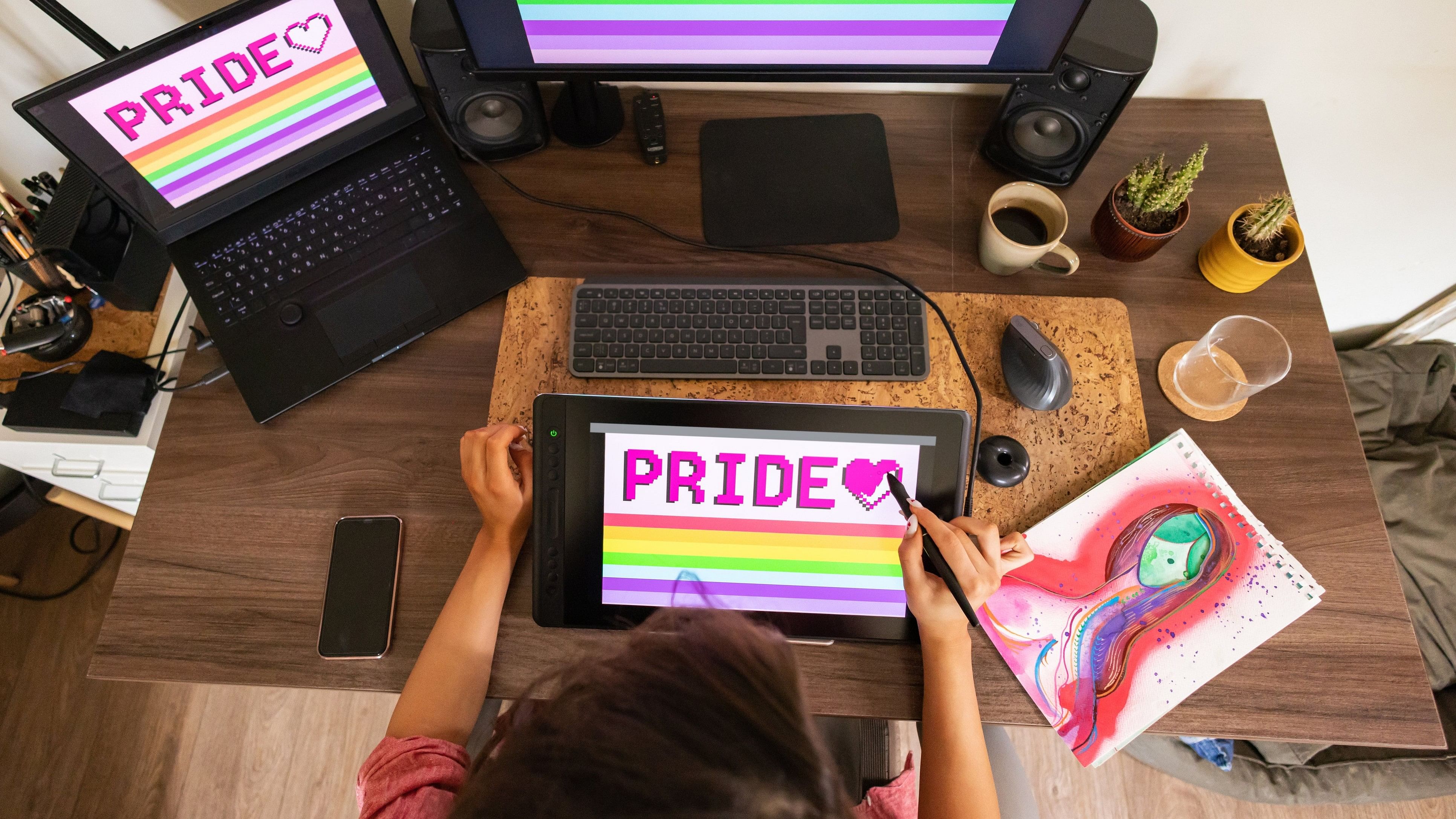 A female graphic designer creating pride-themed artwork on her digital tablet.