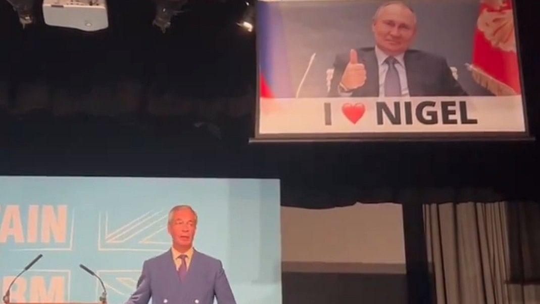 <div class="paragraphs"><p>A banner slowly unfurled behind a speaking Farage, revealing a smiling Putin giving a thumbs-up sign, along with the words 'I (heart emoji) Nigel'.</p></div>