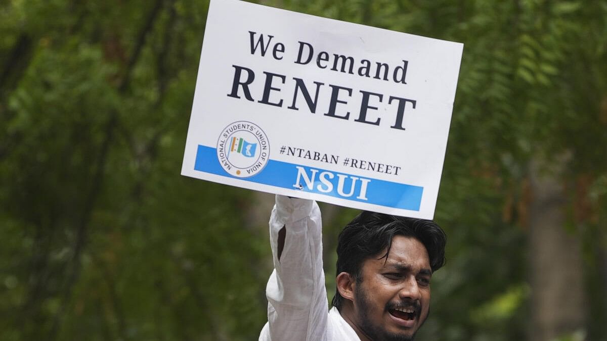 <div class="paragraphs"><p>An NSUI activist holds a placard during ‘Chhattra Sansad Gherav’ protest at Jantar Mantar against the alleged irregularities in NEET-UG and cancellation of UGC-NET exams, in New Delhi.</p></div>