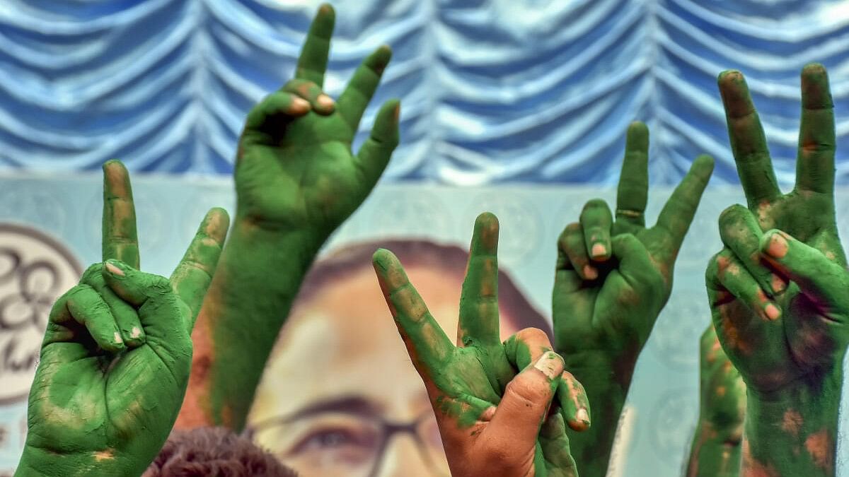 <div class="paragraphs"><p>TMC supporters flash victory signs covered in green 'gulaal' as they celebrate the party's lead during counting of votes for Lok Sabha elections.</p></div>