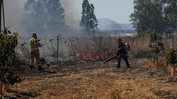 <div class="paragraphs"><p>Israeli fire-fighter and another man work to take control over fire following rocket attacks from Lebanon.</p></div>