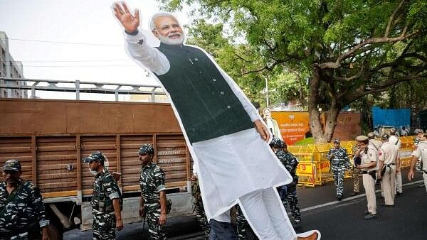 <div class="paragraphs"><p>A person carries a cut-out of Narendra Modi outside BJP headquarters, on the day of the general election results</p></div>