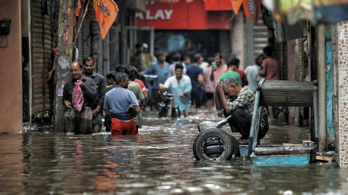 <div class="paragraphs"><p>People wade through a waterlogged road near Sarai Kale Khan area after rain, in New Delhi.</p></div>