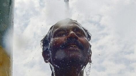 <div class="paragraphs"><p>A labourer cools himself under a water tap to get relief from heat waves on a hot summer day, in Amritsar</p></div>