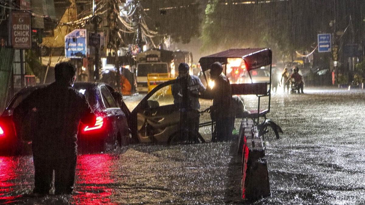 <div class="paragraphs"><p>People wade through a waterlogged road during rain at Jangpura area, in New Delhi, Wednesday, July 31, 2024.</p></div>