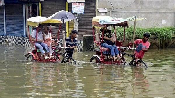 <div class="paragraphs"><p>Rickshaw pullers wade through a flooded street after rainfall, in Guwahati.</p></div>