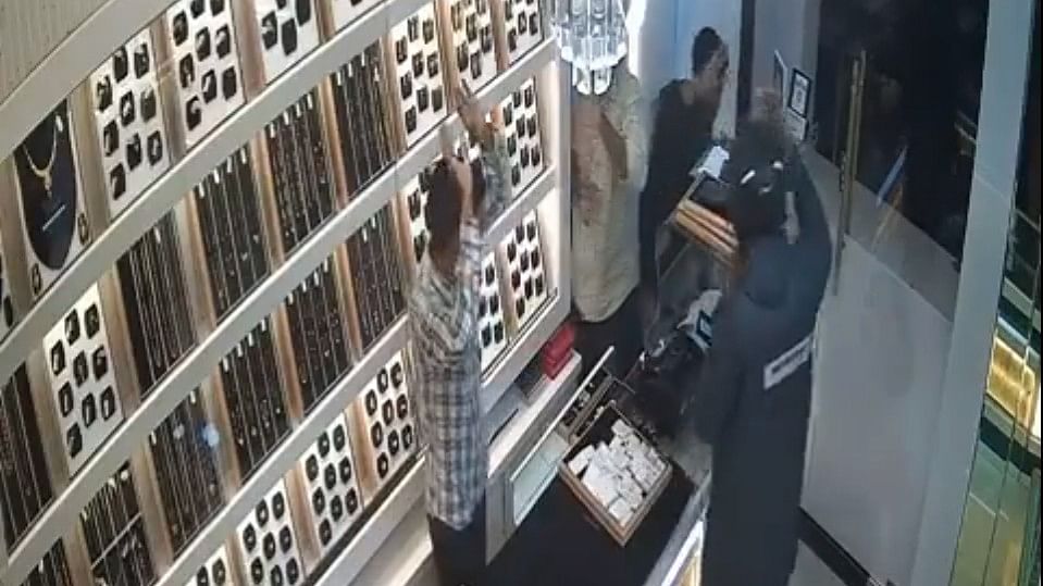 <div class="paragraphs"><p>Screengrab from the CCTV footage showing the robbery at gunpoint in progress. One of the people working at the store can be seen with their hands up</p></div>