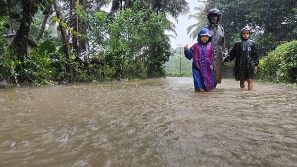 <div class="paragraphs"><p>A man along with children walks through a waterlogged street during rains.</p></div>