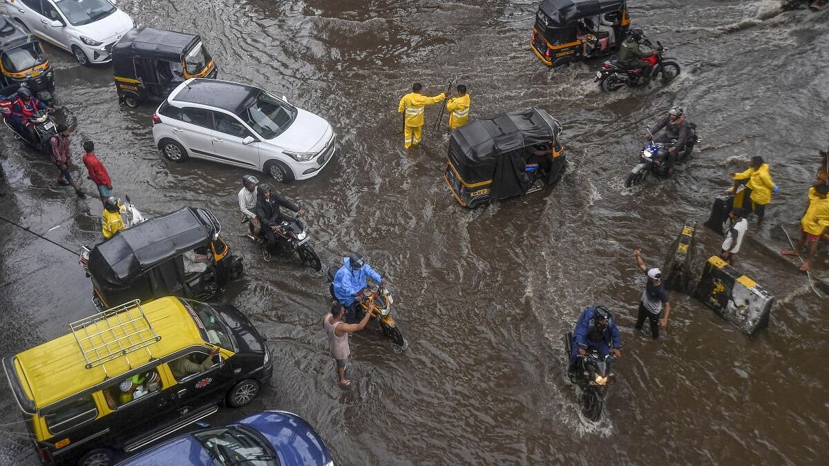 <div class="paragraphs"><p>Commuters wade through a waterlogged street following rains, in Mumbai, Monday on July 8, 2024.</p></div>