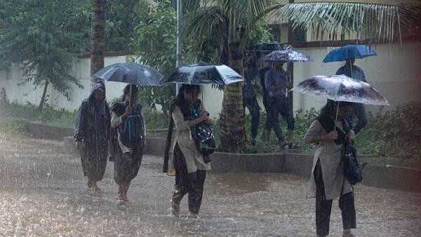 <div class="paragraphs"><p>Students walk amid heavy monsoon rains, in Bhubaneswar.</p></div>