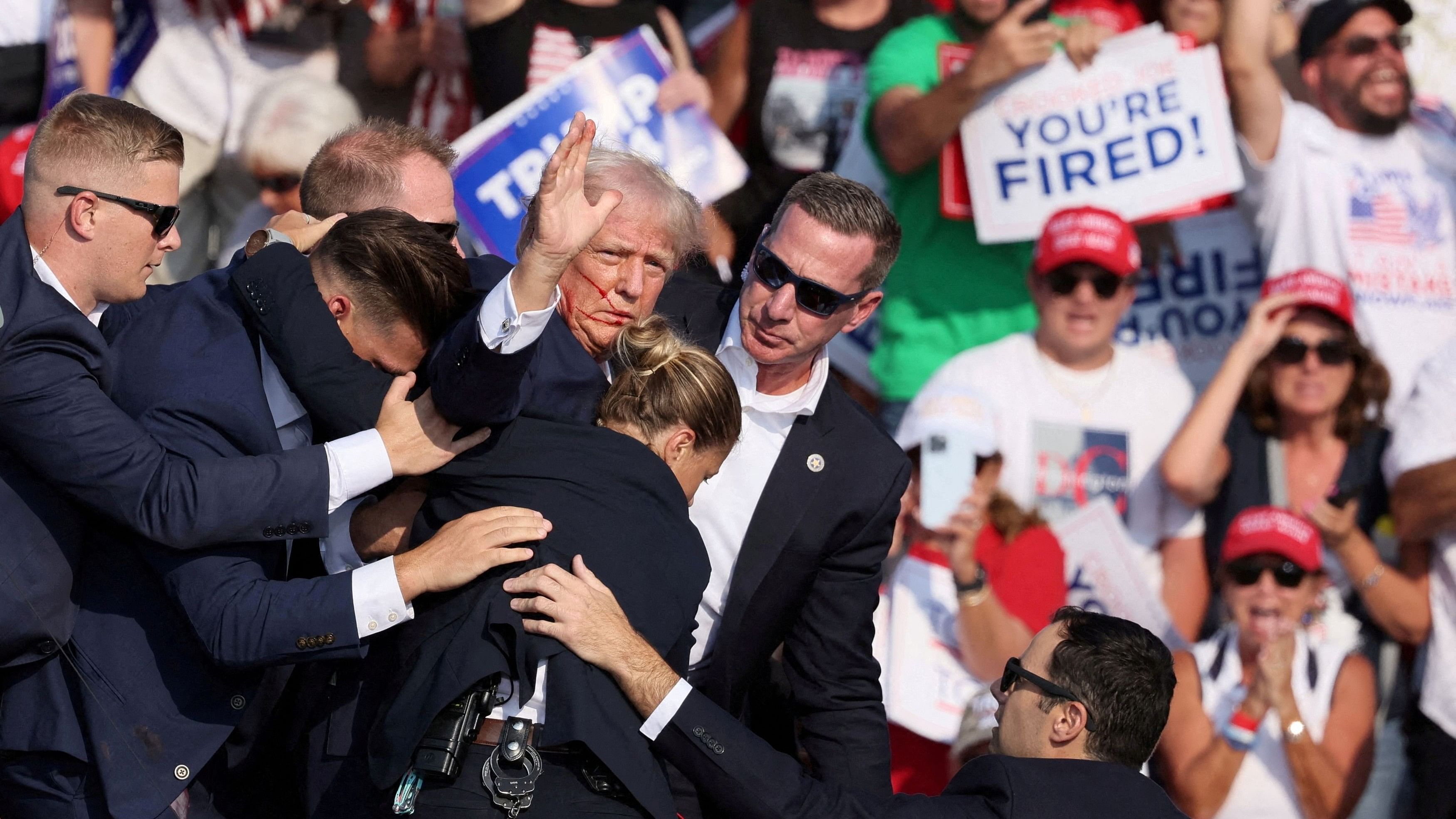 <div class="paragraphs"><p>Republican presidential candidate and former US President Donald Trump gestures with a bloodied face while he is assisted by U.S. Secret Service personnel after he was shot in the right ear during a campaign rally at the Butler Farm Show in Butler, Pennsylvania, U.S., July 13, 2024.</p></div>