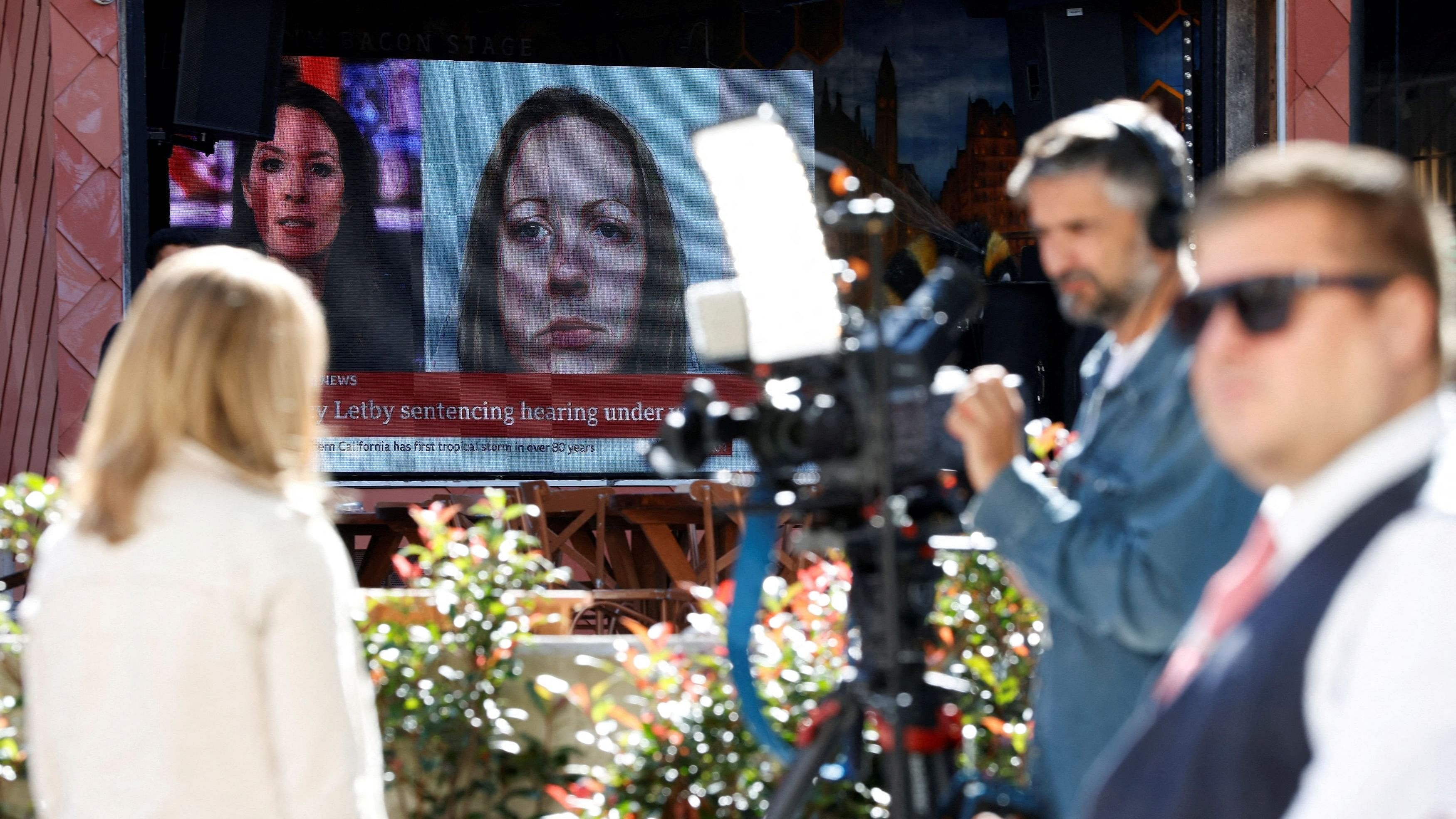 <div class="paragraphs"><p> Members of the media work near a large screen showing a picture of convicted hospital nurse Lucy Letby.</p></div>