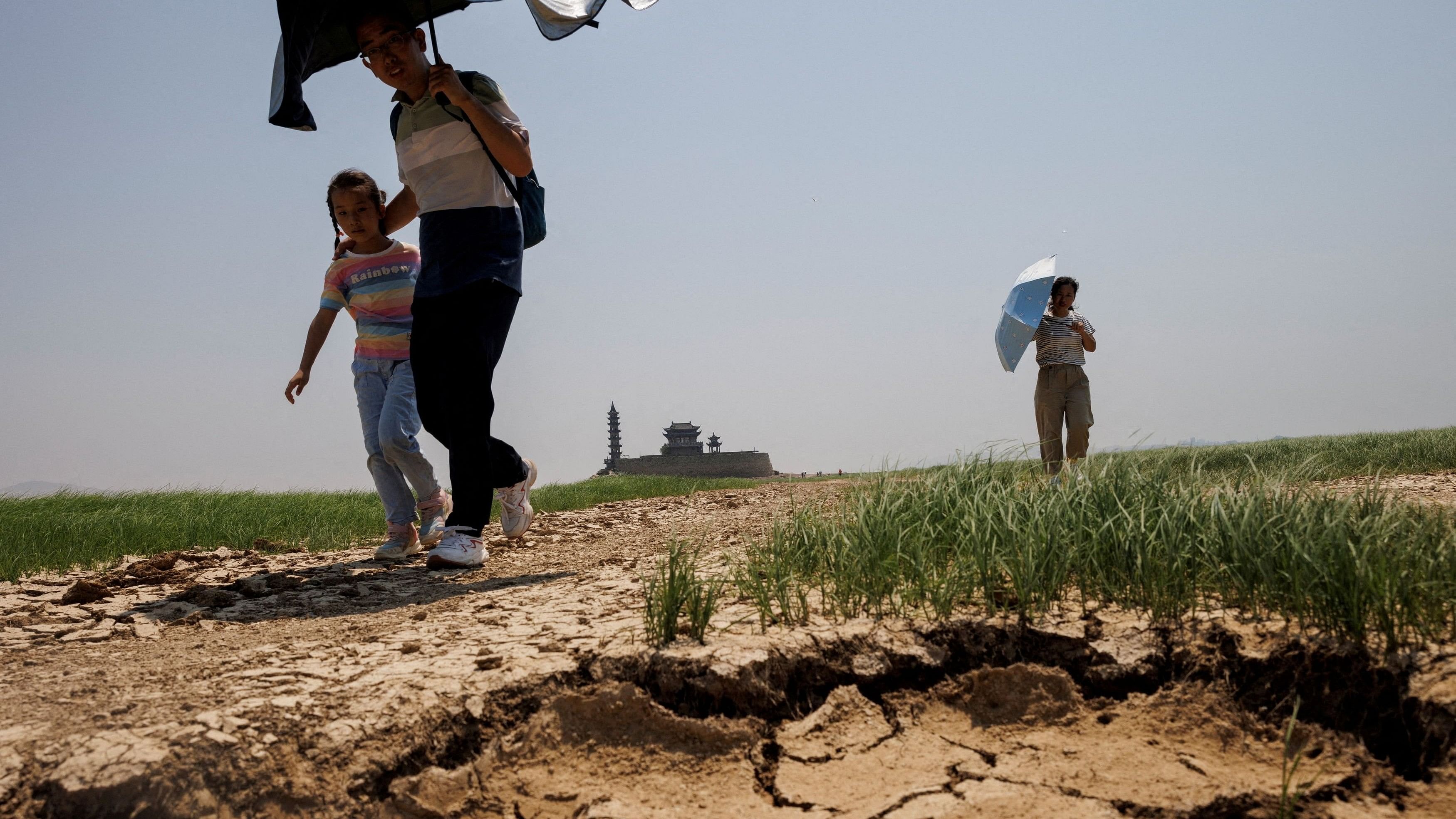 <div class="paragraphs"><p>People walk across a dried-up section of farmlands of southern Sicily</p></div>