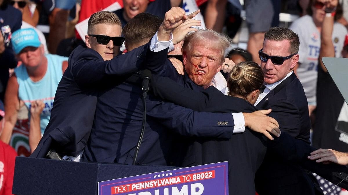 <div class="paragraphs"><p>Republican presidential candidate and former US President Donald Trump gestures with a bloodied face while he is assisted by US Secret Service personnel after he was shot in the right ear during a campaign rally at the Butler Farm Show in Butler, Pennsylvania, US on July 13, 2024.</p></div>