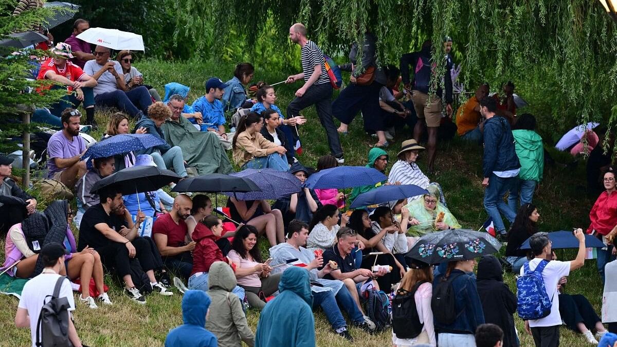 <div class="paragraphs"><p>Spectators are seen taking cover from rain ahead of the opening ceremony.</p></div>