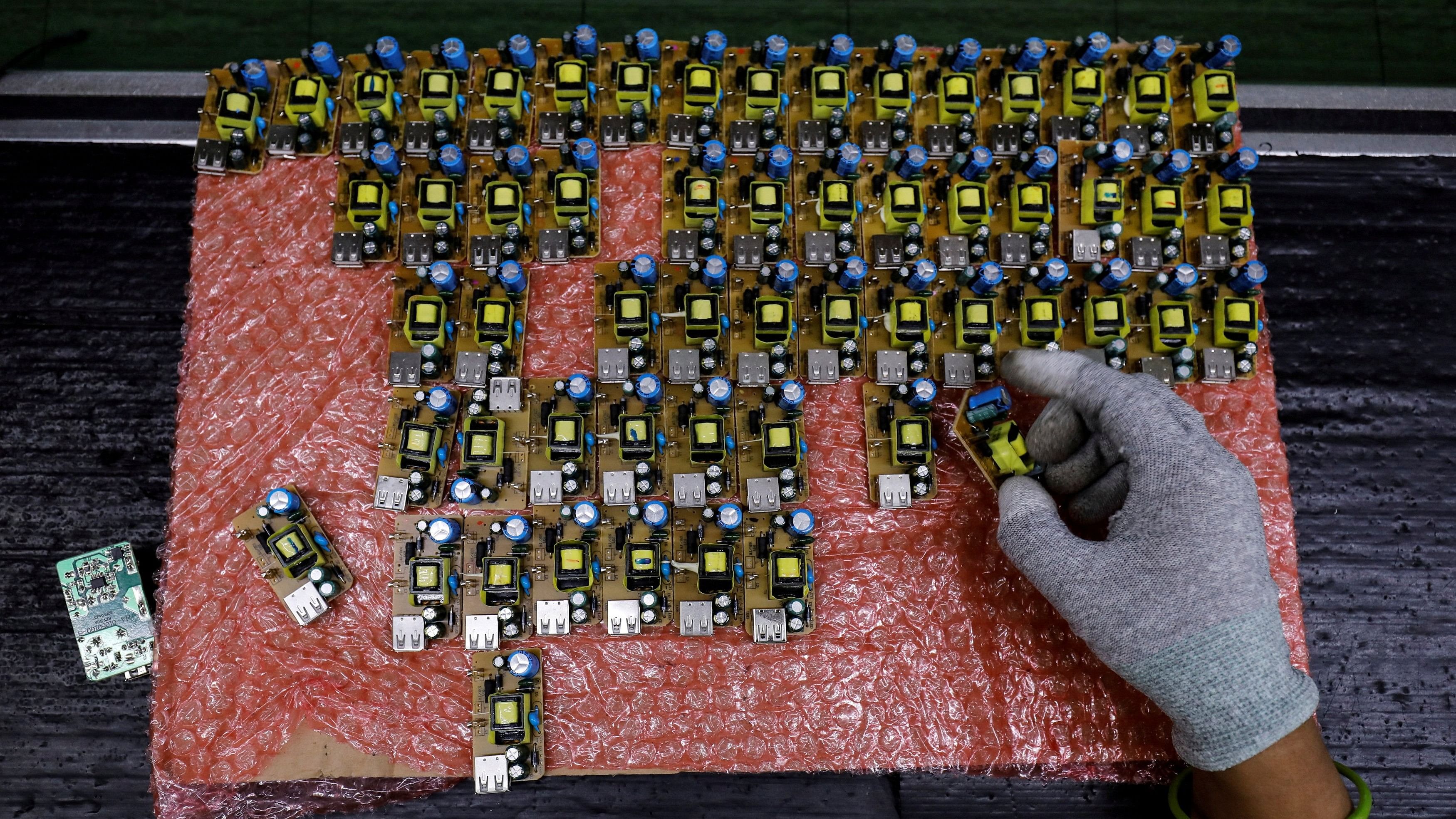 <div class="paragraphs"><p>A worker arranges battery charger circuit boards at a mobile phone battery manufacturing plant in Noida, India on October 12, 2018.</p></div>