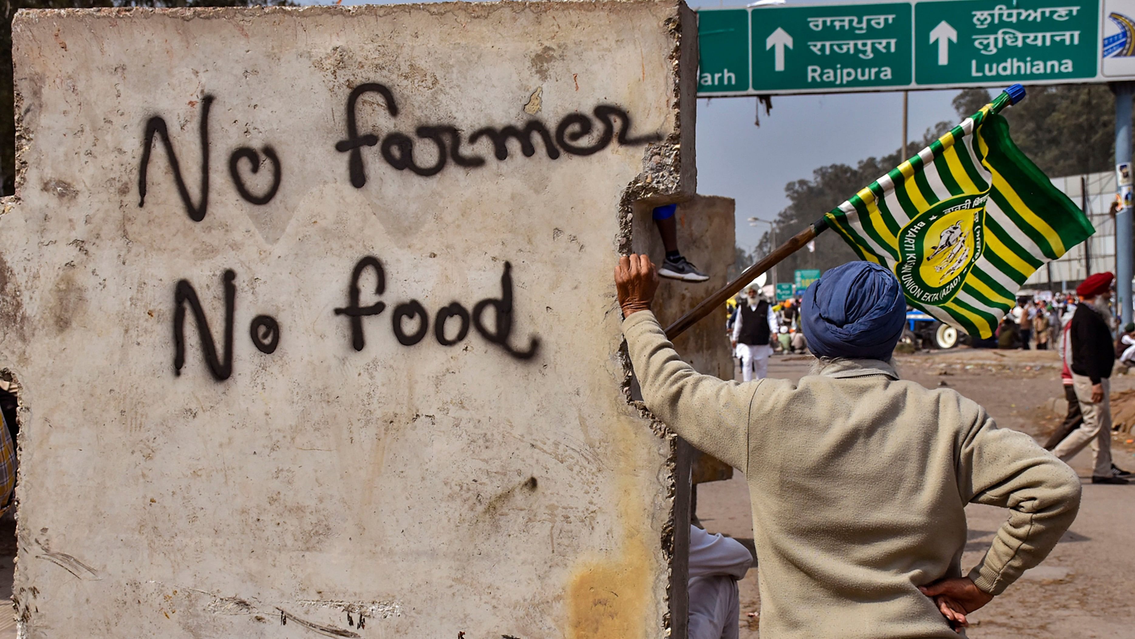 <div class="paragraphs"><p>A farmer stands next to a roadblock with inscription reading 'No farmer, no food' during the  farmers' protest over the ruling party's refusal to implement a legal guarantee of minimum support price (MSP) for crops, at the Punjab-Haryana Shambhu Border, in Patiala district</p></div>