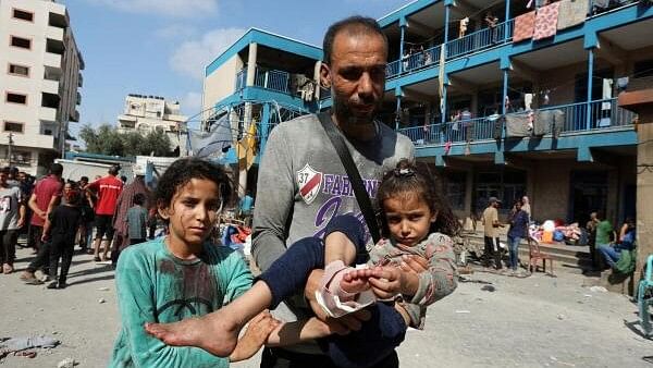 <div class="paragraphs"><p>A Palestinian man carries a wounded child as people gather at the site of an Israeli air strike on a UN school sheltering displaced people, amid the Israel-Hamas conflict, in Nusairat in central Gaza Strip, July 14, 2024.</p></div>