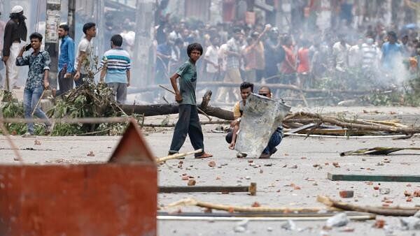 <div class="paragraphs"><p>Protesters shield themselves with a metal sheet during a clash with Border Guard Bangladesh (BGB) and the police outside the state-owned Bangladesh Television as violence erupts across the country after anti-quota protests by students, in Dhaka, Bangladesh, July 19, 2024. </p></div>