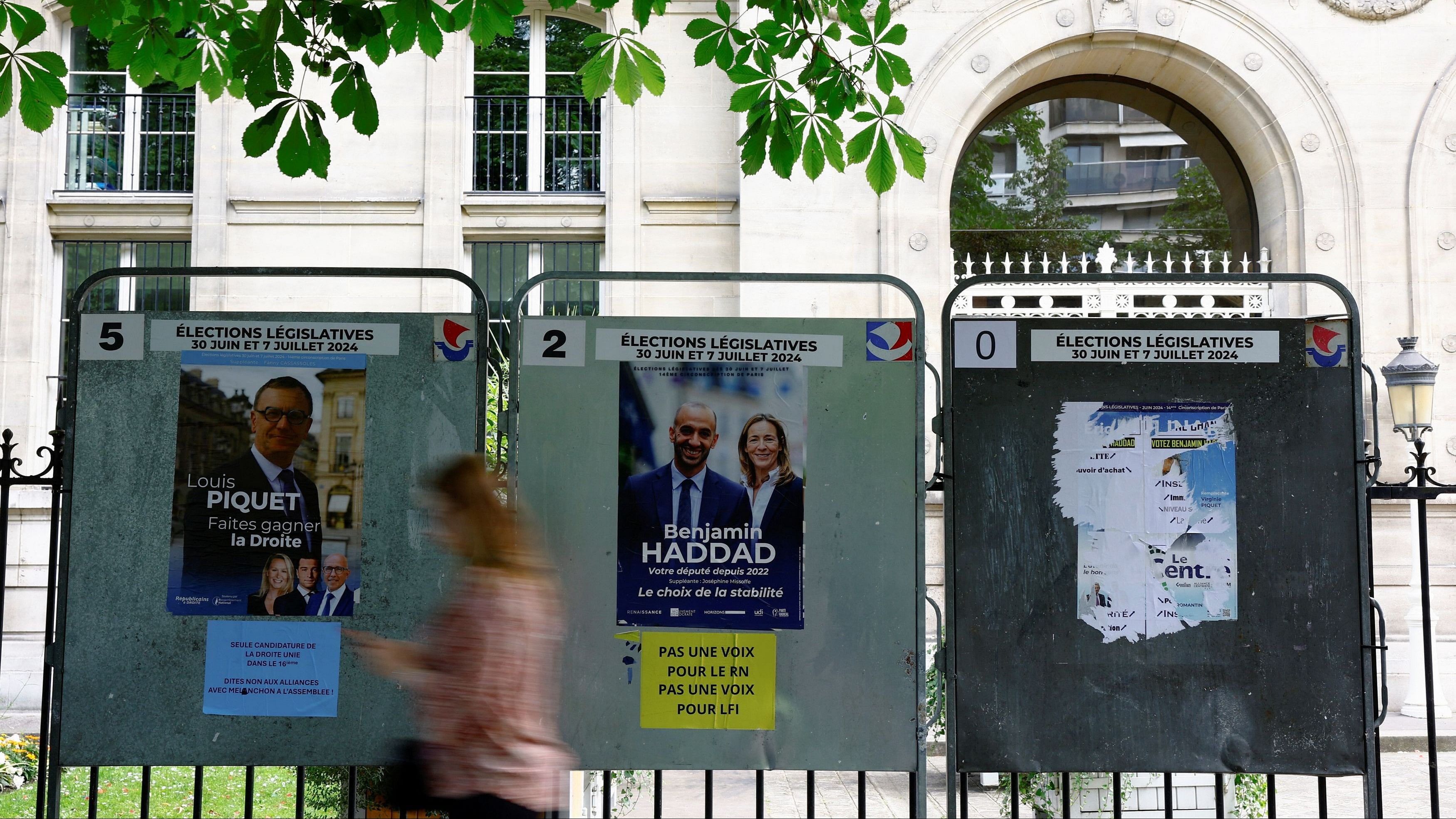 <div class="paragraphs"><p>A woman walks past campaign posters on an election board prior to the second round of the early French parliamentary elections, in Paris, France</p></div>