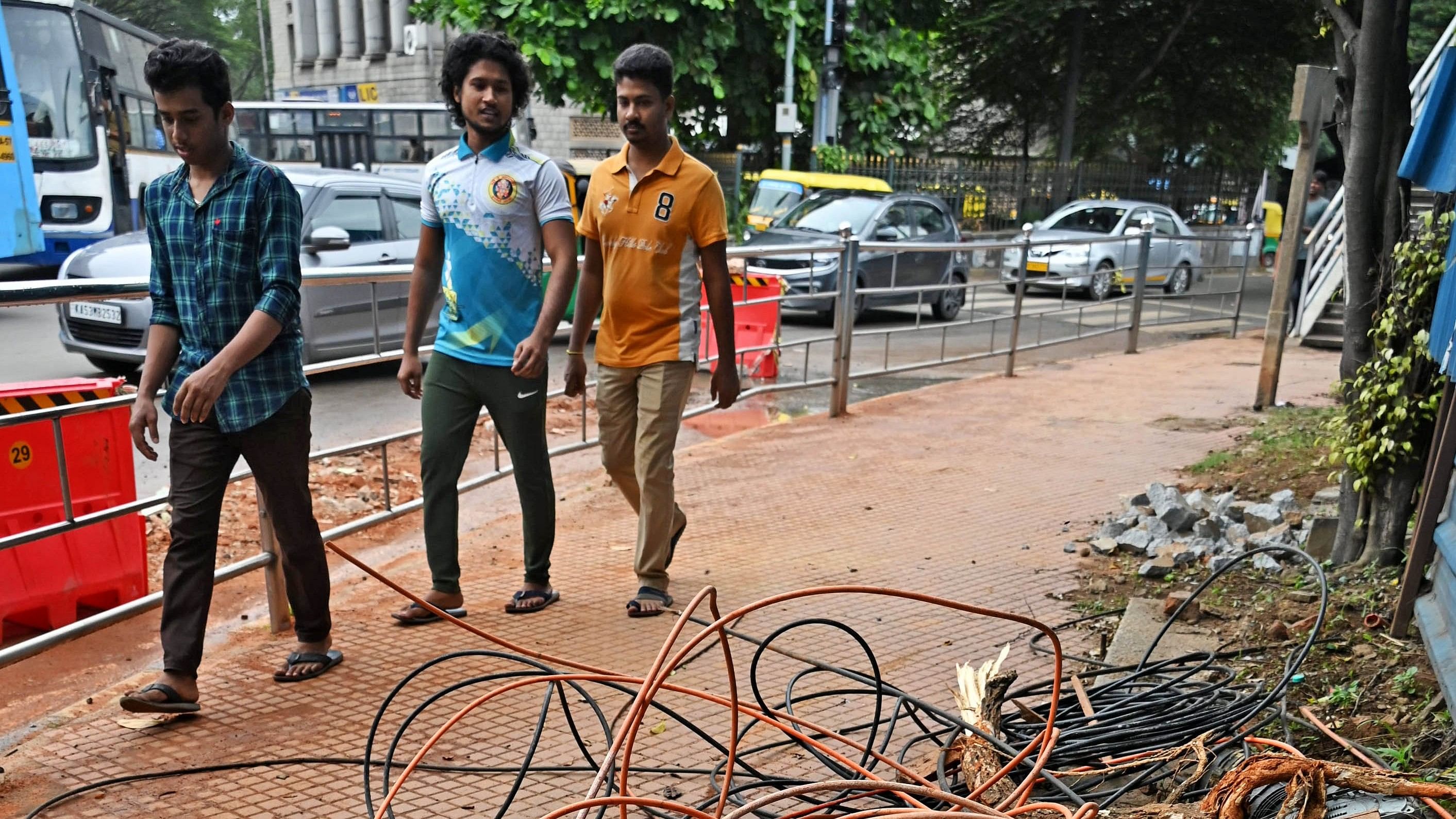 <div class="paragraphs"><p>Pedestrians walk past bundled optical fibre cables occupying the footpath near the Halasuru Gate traffic police station.</p></div>