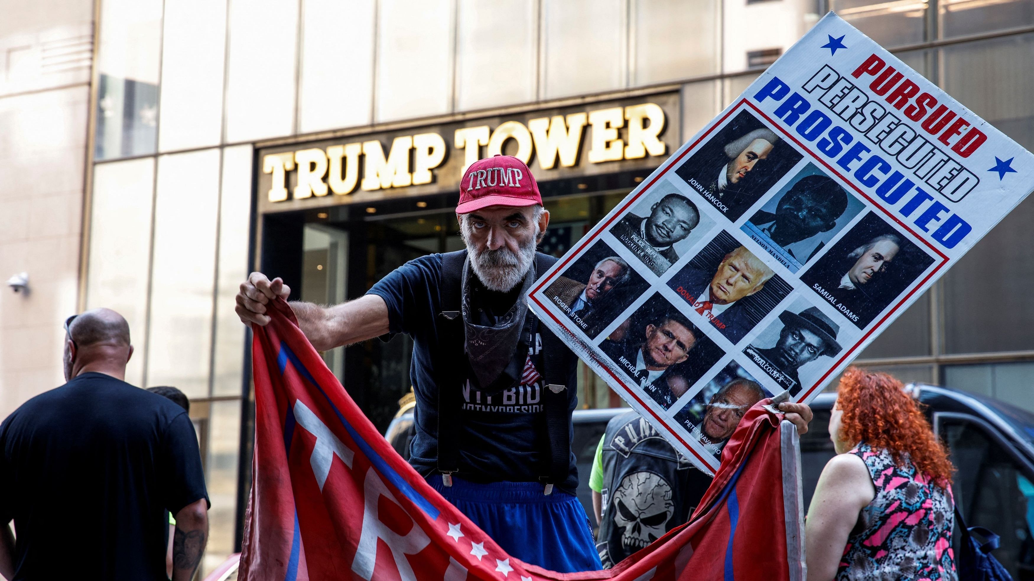 <div class="paragraphs"><p>A man holds a flag and a placard in support of former U.S. President Trump after he was injured during a campaign rally, at Trump Tower in New York</p></div>