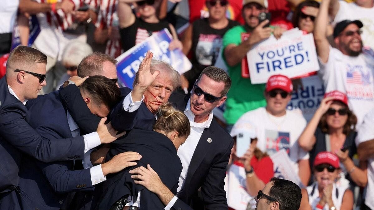 <div class="paragraphs"><p>Republican presidential candidate and former US President Donald Trump gestures with a bloodied face while he is assisted by US Secret Service personnel after he was shot in the right ear during a campaign rally.</p></div>