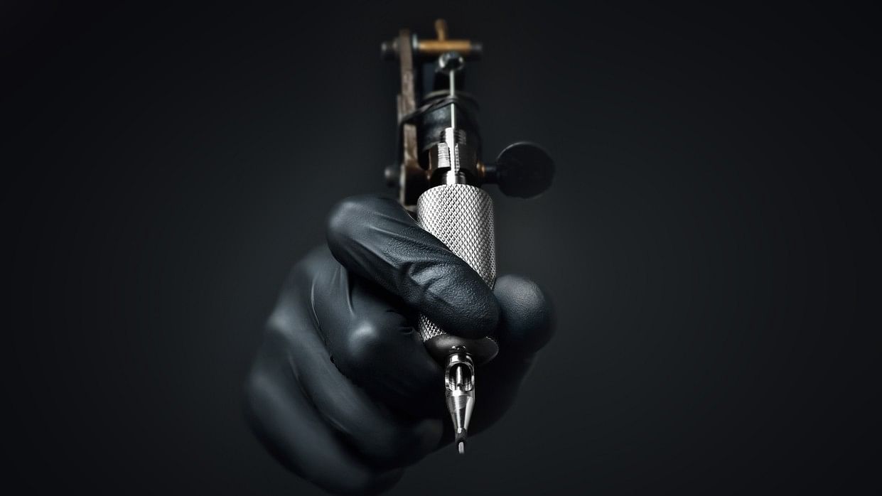 <div class="paragraphs"><p>Tattoo artist holding tattoo machine on dark background. Representative image.</p></div>