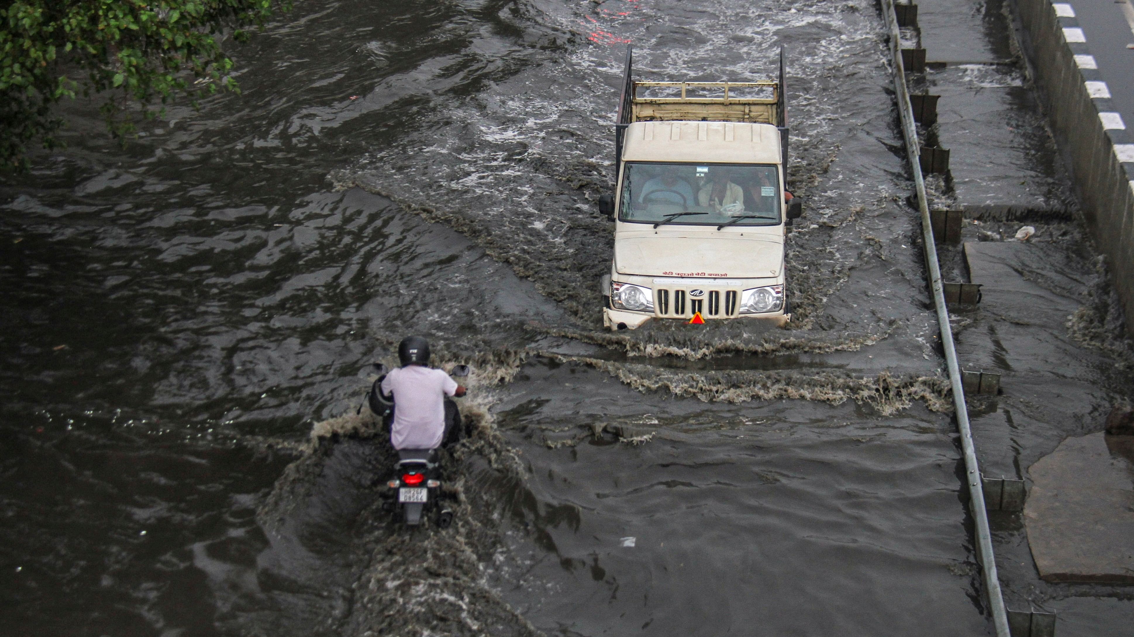 <div class="paragraphs"><p>Vehicles move through a waterlogged service road in Delhi.</p></div>