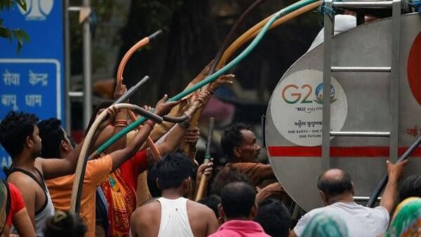 <div class="paragraphs"><p>People use pipes to collect drinking water from a tanker that comes twice a day at Vivekananda Camp</p></div>