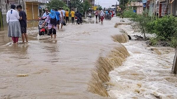 <div class="paragraphs"><p>Commuters pass through a waterlogged road after heavy rainfall in Nagpur on Saturday, July 20, 2024. </p></div>