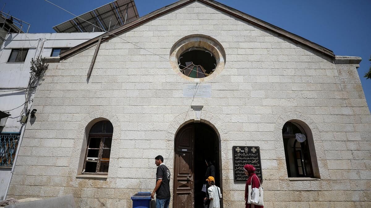 <div class="paragraphs"><p>Palestinians stand outside the Baptist Church which was damaged during Israel's military offensive and turned into a clinic as the wounded crowd the hospitals, amid Israel-Hamas conflict, in Gaza City.</p></div>