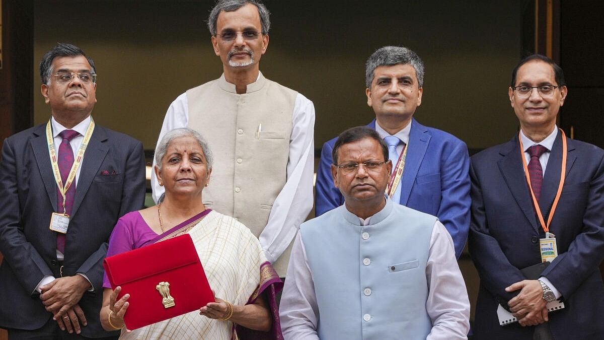 <div class="paragraphs"><p>Union Finance Minister Nirmala Sitharaman displays a red pouch carrying the Budget documents after she arrived at the Parliament to present the Union Budget 2024-25.&nbsp;Finance MoS Pankaj Chaudhary and Chief Economic Advisor V. Anantha Nageswaran are also seen.</p></div>