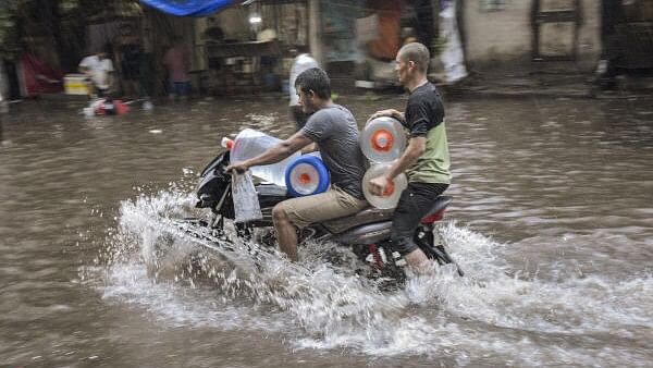 <div class="paragraphs"><p>Commuters wade through a waterlogged street following rains, in Surat<strong>.</strong></p></div>