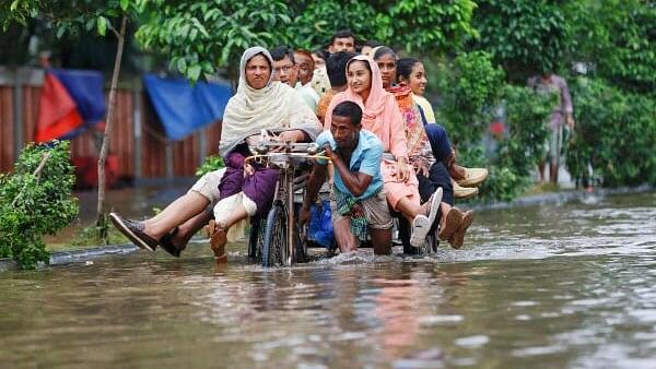 <div class="paragraphs"><p>In this file photo,&nbsp;commuters ride on a rickshaw on a flooded road after heavy rains in Dhaka, Bangladesh.</p></div>