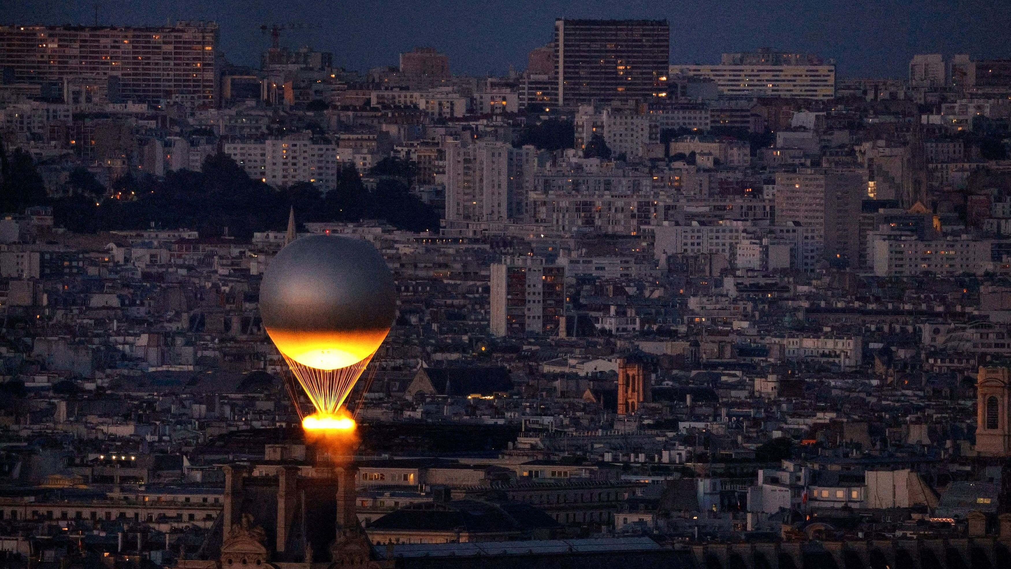 <div class="paragraphs"><p>The Olympic cauldron is lit with the Olympic flame as it flies above Paris while attached to a balloon.</p></div>